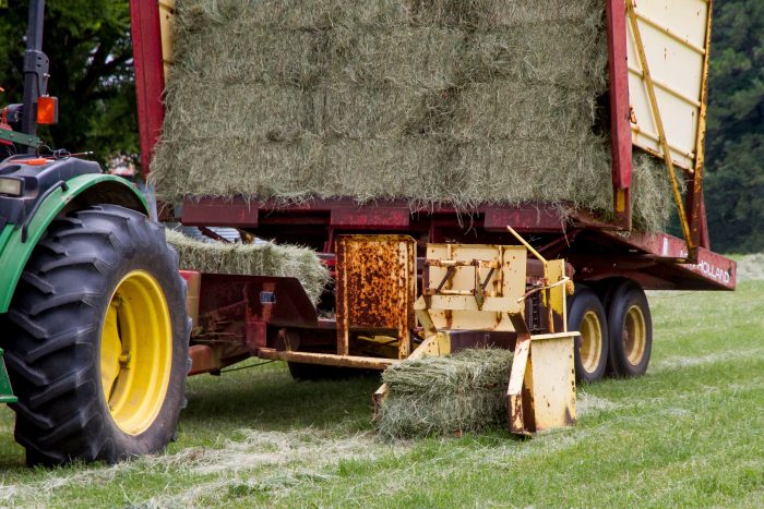 Square Baler Working in Field – Licensed Stock Photograph Real photograph of a tractor and square baler working in a farm field; illustrative straw and hay production scene